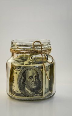 Fotokopi alanı, birikimlerle dolu beyaz arka plandaki kavanozda 100 Amerikan doları var.
