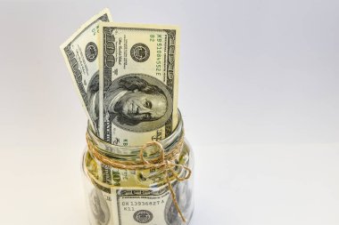 Fotokopi alanı, birikimlerle dolu beyaz arka plandaki kavanozda 100 Amerikan doları var.