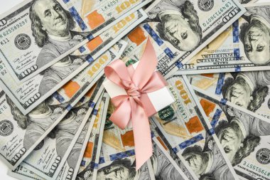 Amerikan dolarlarının arka planında punk kurdelesi olan beyaz hediye kutusu