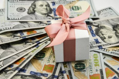 Amerikan dolarlarının arka planında punk kurdelesi olan beyaz hediye kutusu