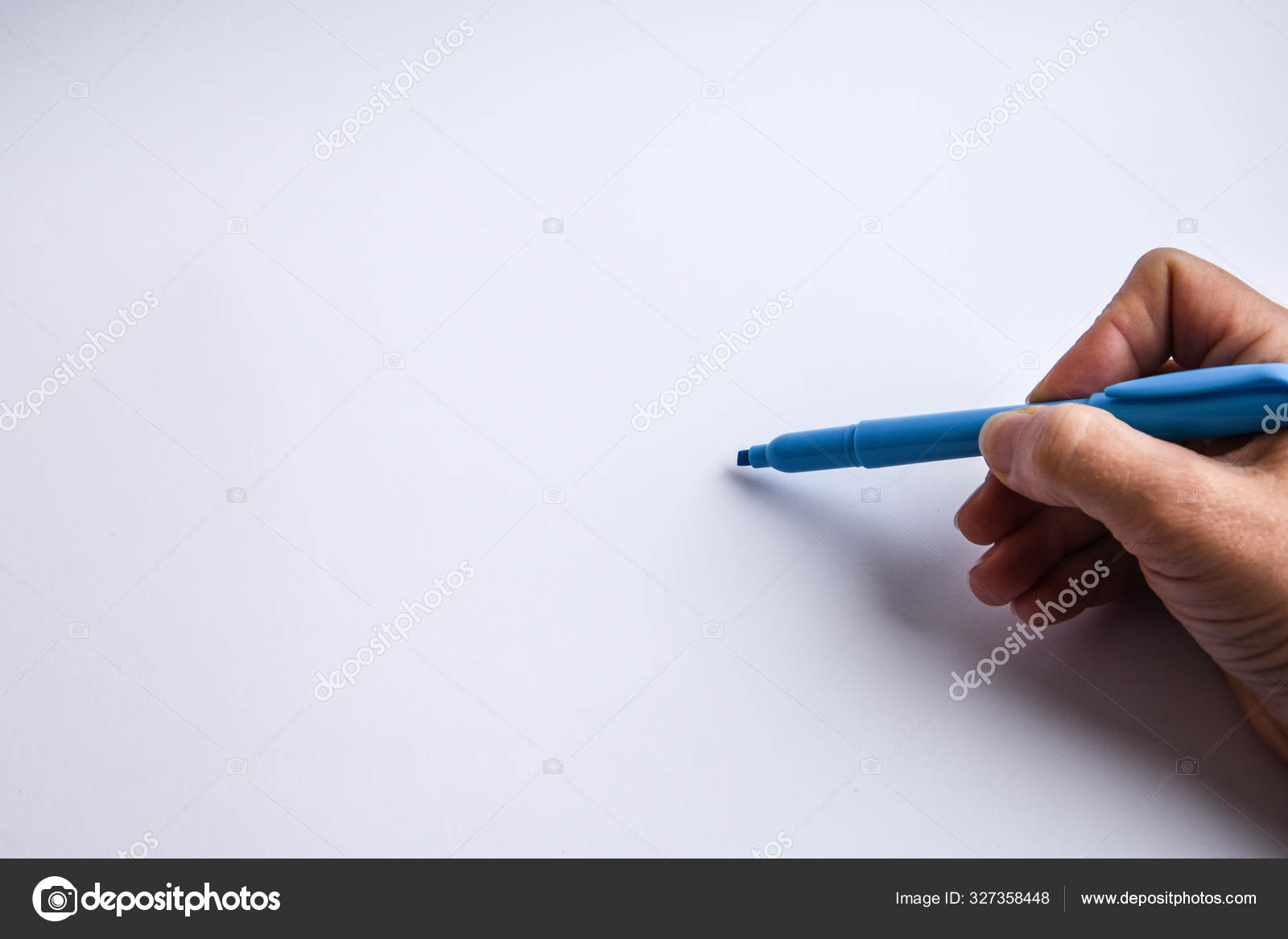 Hand holding a pen and writing something on the white background