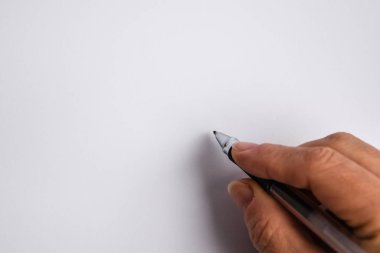 Bir kalem tutan ve beyaz arka plana bir şeyler yazan bir el.