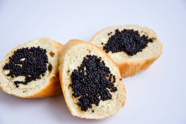 Beyaz arka planda siyah havyarlı üç sandviç.