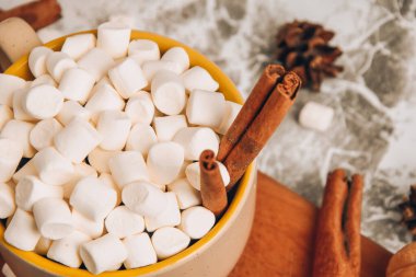 Bir fincan yeni yıl lezzetli sıcak çikolata ve üzerine kakao tozu, koni ve kruvasan serpiştirilmiş kakao gri bir masada tarçın, seçici bir odak noktası.