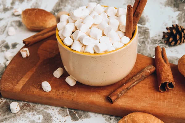 Secangkir Natal Tahun Baru lezat coklat panas dan coklat dengan marshmallow ditaburi dengan bubuk kakao, kerucut dan croissant, kayu manis di atas meja abu-abu, fokus selektif — Stok Foto