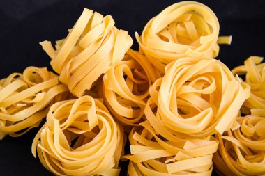 Pasta all 'uovo, Tagliatelle Pasta, siyah arka planda yuvarlak ham makarna topları.
