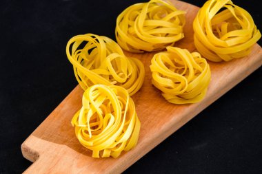Pasta all 'uovo, Tagliatelle Pasta, siyah arka planda yuvarlak ham makarna topları.