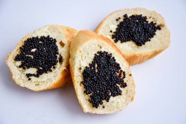 Beyaz arka planda siyah havyarlı üç sandviç.