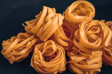 Pasta all 'uovo, Tagliatelle Pasta, siyah arka planda yuvarlak ham makarna topları.