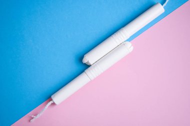 Mavi ve pembe arka planda hijyenik tamponlar. Fotokopi alanı, kadınların hijyen koruması için adet öncesi hijyenik tampon. Kritik günler. Tıbbi kavram