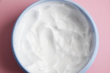 Pembe arka planda mavi bir kavanozda kozmetik krem. Cilt bakımı seçici odak