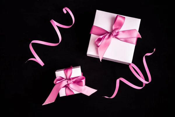 Подарочные коробки с розовой лентой и украшения на темном черном фоне — стоковое фото