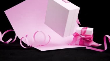Pembe ve siyah arka planda pembe kurdeleli mevcut kutu. 360 derece dönüş, kusursuz döngü. Yer çekimi sıfır. Havalanma, tatil konsepti, hediyeler