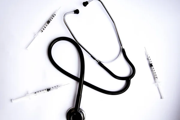 Lékařský stetoskop s injekčními stříkačkami na bílém pozadí — Stock fotografie