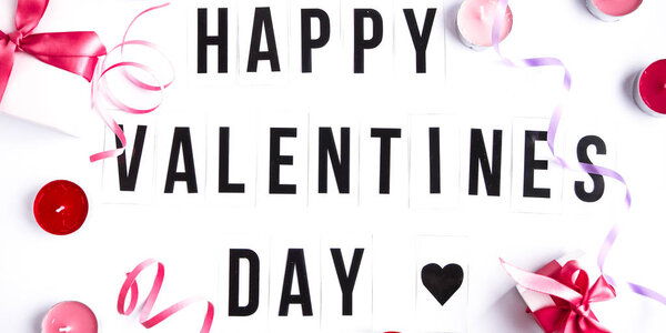 Happy valentines day text on white table background, with gift boxes and candles