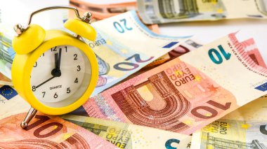 Alarm clock with paper euro money 10, 20, 50, 100, alarm clock on banknotes, time is money