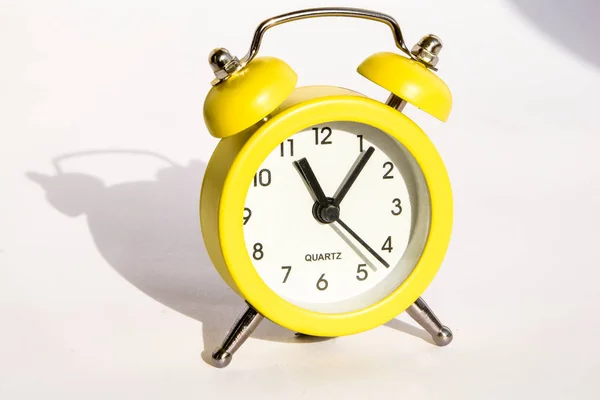 Reloj despertador amarillo con gran sombra sobre fondo blanco, espacio para copiar —  Fotos de Stock