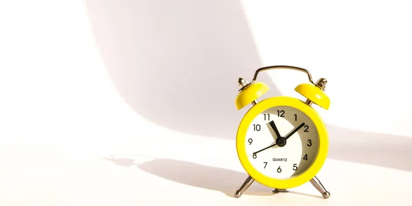Reloj despertador amarillo con gran sombra sobre fondo blanco, espacio para copiar —  Fotos de Stock