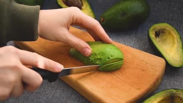 Female hands cut avocado in pieces . Avocado with black dots. Fresh ripe avocado — ストック動画