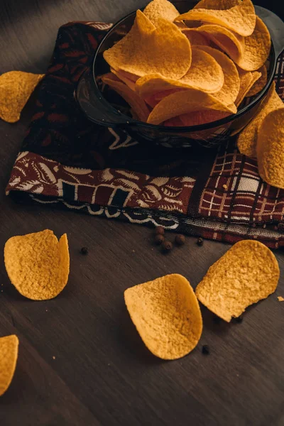 Crispy potato chips in bowl with pepper and kitchen towel