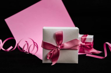 Pembe ve siyah arka planda pembe kurdeleli mevcut kutu.