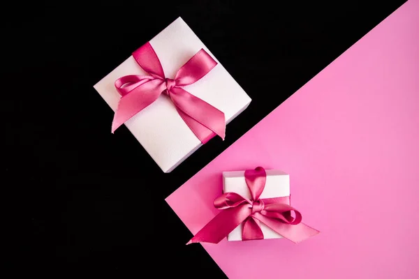 Представляем коробки с розовой лентой на розовом и черном фоне — стоковое фото