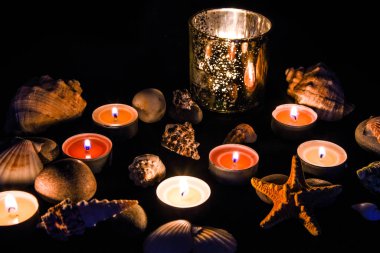 Mumlar, taşlar ve kabuklar kaplıcada, geceleri ışık, deniz kaplıcası konsepti, spa tedavisinin bileşimi, seçici odak noktası