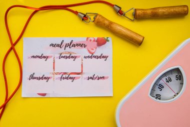 Zemin pulları, sarı arka planda ip atlama. Yemek organizatörü, planlama fitness. Zayıflama konsepti, fitness eğitimi. Stüdyo çekimi. Üst Görünüm, Boşluğu Kopyala