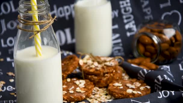 Drinking milk from straw glass old fashioned bottle with cookies on background — Stok video