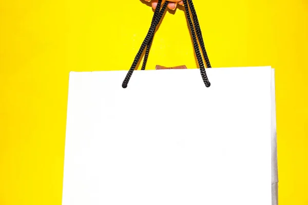 Weibliche Hand Hält Weiße Einkaufstasche Auf Gelbem Hintergrund Kopierraum Shopping — Stockfoto