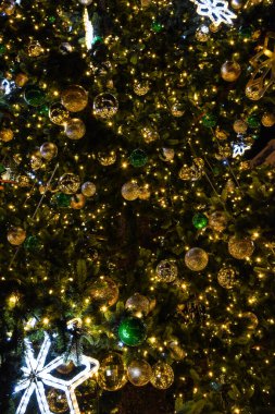 Geceleri hafif kar taneleri ve baloları olan Noel ağacı.