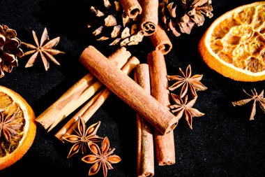 Kuru portakal dilimleri, tarçın ve yıldız anasonlarının arka planı, hazırlanmak için malzemeler, siyah arka planda sıcak şarap, Noel baharatları.