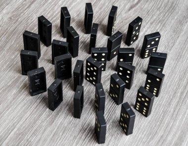 Açık tahta bir masa üzerindeki siyah dominolar art arda dururlar, seçici odak, eski siyah, karton arka planda klasik dominolar. Oyun dominoları konsepti
