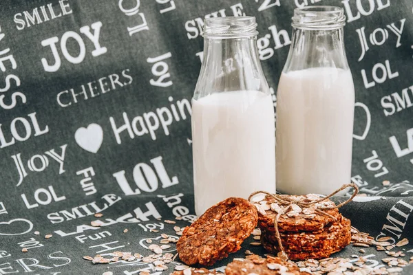 Oat and peanut butter cookies, close up with bottles of milk, homemade oatmeal cookies with chocolate and banana with almond