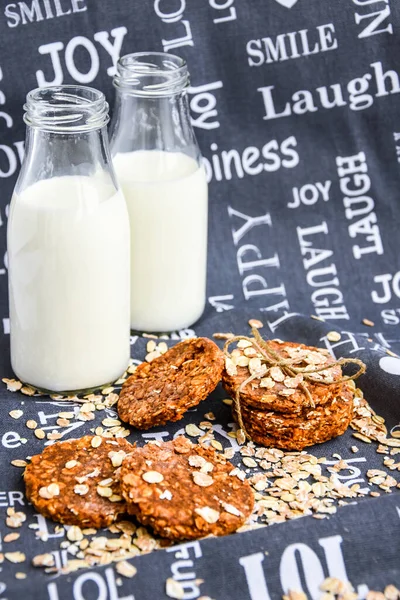 Oat and peanut butter cookies, close up with bottles of milk, homemade oatmeal cookies with chocolate and banana with almond