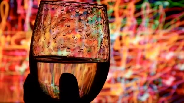 Waving gold white wine in a glass on defocused dark background . Beautiful stock footage for wine commercial . sommelier mixing wine in glass evaluating color at tasting. Shot in Slow Motion