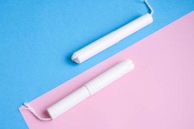Mavi ve pembe arka planda hijyenik tamponlar. Fotokopi alanı, kadınların hijyen koruması için adet öncesi hijyenik tampon. Kritik günler. Mavi arka planda tıbbi gebelik, günlük, adet gören kadın.