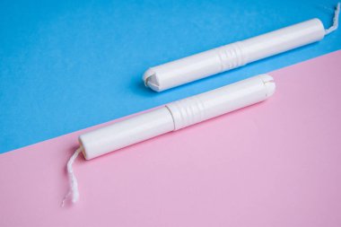 Mavi ve pembe arka planda hijyenik tamponlar. Fotokopi alanı, kadınların hijyen koruması için adet öncesi hijyenik tampon. Kritik günler. Mavi arka planda tıbbi gebelik, günlük, adet gören kadın.