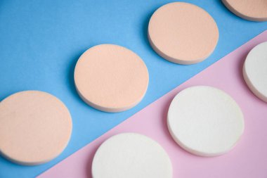 Mavi ve pembe arkaplanda beyaz ve bej makyaj süngerleri yakın çekim yüz makyajı için kozmetik süngerler, kozmetik süngerler, güzellik konsepti.