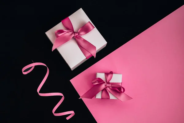 Pembe ve siyah arkaplanda pembe kurdeleli mevcut kutular, Tatil konsepti, dekorasyonlar, kopyalama alanı, üst görünüm, tebrik kartı