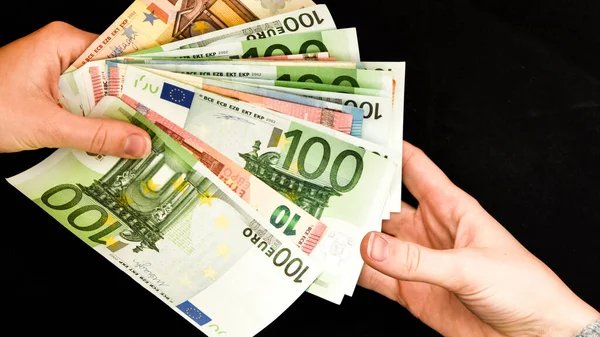 hand giving euro isolated on black background, Hand holding euros, Trading Business Theme, one hundred money banknotes
