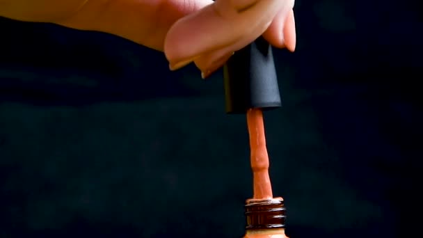 A drop of nail polish drips into an open bottle on a black background. Advertising gel-lacquer for nails of bright color. Slow drop drops of nail gel varnish into the bubble. Orange color — Stock video