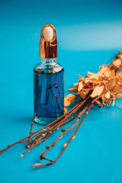 Aging Serum Glazen Fles Met Druppelaar Blauwe Achtergrond Droge Bloemen — Stockfoto