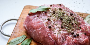 Çiğ domuz omuzu ve baharat. Koyu yaprak, ahşap arka planda, kapak, baharatlı taze çiğ et, fileto, kürek, boyun, arka bacak bifteği üzerine siyah biber