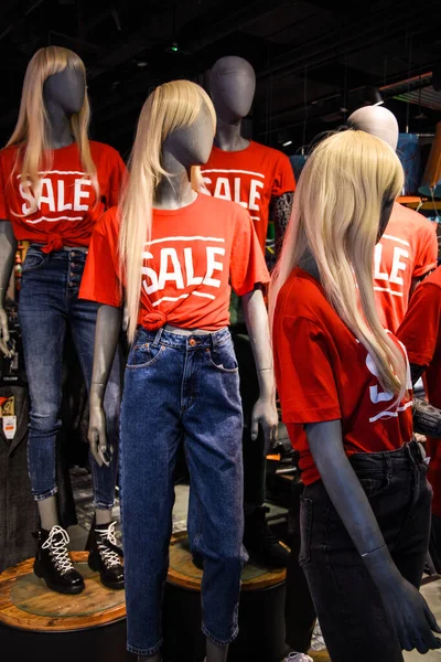 decoration of the entrance to the store in the mall. signboard sale with white letters on a red background.discounts at the mall, Mannequins in a window of a clothing store in T-Shirts With Signs Advertising Sale