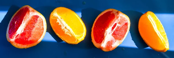 コピースペースのある青色の背景にスライスしたグレープフルーツとオレンジのトップビュー 異なる柑橘類のカット作品 スライスした柑橘類のフルーツジューシーな — ストック写真