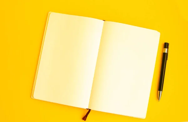 黄色い背景のペン付きブランクノートブックのトップビュー フリーランスの作業環境ビュー コピースペース ヘッドフォン — ストック写真