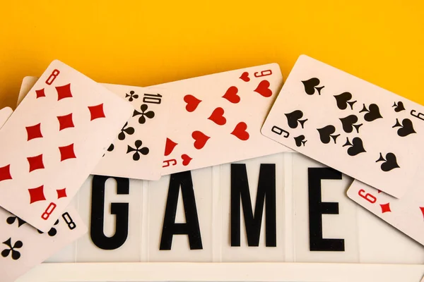 Sarı arkaplanda oyun kartları, masa oyunları, masa oyunları ve sarı arkaplanda Scrabble harfleri olan ışık kutusundaki oyun gecesi metni Oyun Gecesi