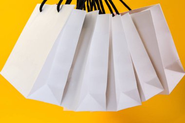 Sarı arka planda alışveriş yapmak için beyaz kese kağıdı seti. Düz metin veya ürün için tasarım, kopyalama alanı, alışveriş poşeti ve kopyalama alanı