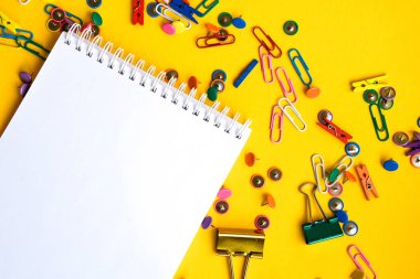 Ofis malzemeleri renkli düğmeler ve boş not defterli ataçlar sarı arka planda kopya alanı olan ofis masası araçları iş için